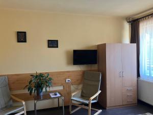 - un salon avec 2 chaises, une télévision et une armoire dans l'établissement Adél Apartman, à Sárvár