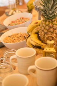 einen Tisch mit Tassen und Schalen mit Müsli und Obst in der Unterkunft Niddo Suesca in Suesca