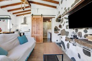 a living room with a couch and a tv on a stone wall at Ca Lajares in Lajares