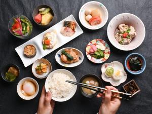 une personne tenant des baguettes sur une table avec des bols de nourriture dans l'établissement Mitsui Garden Hotel Kanazawa, à Kanazawa