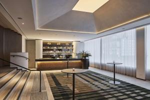 eine Hotellobby mit 2 Tischen und einer Bar in der Unterkunft Rydges Melbourne in Melbourne