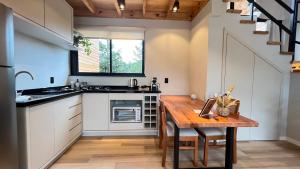 a kitchen with a wooden table and a counter top at Cabanas Jardim de Tereza in São Joaquim