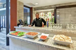 Un uomo in piedi dietro un bancone con del cibo di Embassy Suites by Hilton Minneapolis Airport a Bloomington