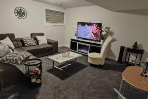 een woonkamer met een bank en een tv bij BlissfulAbode Basement Suite in Airdrie