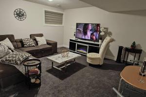 een woonkamer met een bank en een flatscreen-tv bij BlissfulAbode Basement Suite in Airdrie