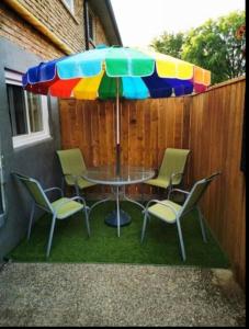 une table et des chaises sous un parapluie coloré dans l'établissement Patio privé, hébergement équipé et spacieux., à Hamilton