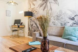 uma sala de estar com um vaso com flores sobre uma mesa em Le grand Arth&M Clermont Ferrand em Clermont-Ferrand