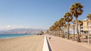 - une plage avec des palmiers et des personnes qui s'y promènent dans l'établissement Apartamento en el Zapillo, Las Conchas II, à Almería