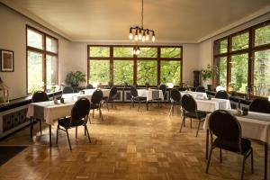 uma sala de jantar com mesas, cadeiras e janelas em Hotel Mühlental em Wernigerode