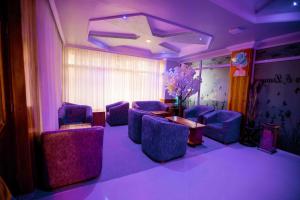 a room with purple chairs and a table and flowers at HADJENS HOTEL in Mwanza