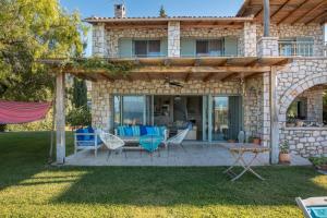 uma casa de pedra com um pátio com cadeiras azuis em Villa Leon em Chalkida