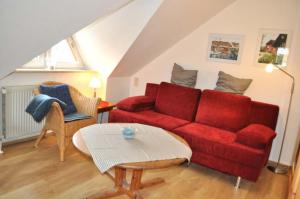 sala de estar con sofá rojo y mesa en Haus Windrose Ferienwohnung Nr 16 en Niendorf