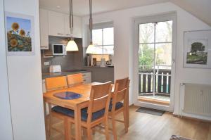 cocina y comedor con mesa de madera y sillas en Haus Windrose Ferienwohnung Nr 16 en Niendorf