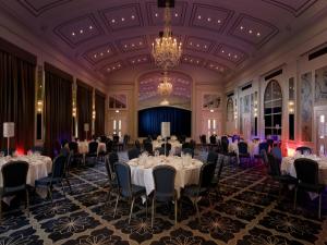 een balzaal met tafels en stoelen en een kroonluchter bij Castle Hotel Windsor in Windsor