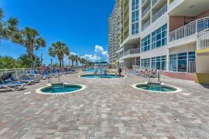 - un patio dans un complexe avec 2 piscines et des chaises longues dans l'établissement Luxury Oceanfront Condo with Resort Amenities!, à Myrtle Beach