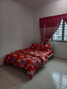 een slaapkamer met een bed met een rood dekbed en een raam bij Homestay UmahMak in Bandar Puncak Alam