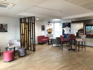 a waiting room with stools and tables and chairs at Ace Hotel Issoire in Issoire