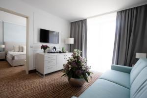 Habitación de hotel con cama, sofá y flores en Thermal Hotel Visegrád en Visegrád