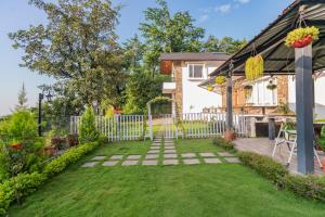 einen Hinterhof mit einem weißen Zaun und Gras in der Unterkunft SaffronStays Wildernest, Dehradun - pet-friendly Swedish home amidst nature in Dehradun