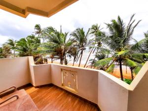 uma varanda com vista para a praia e palmeiras em Hotel Coconut Bay em Kalutara