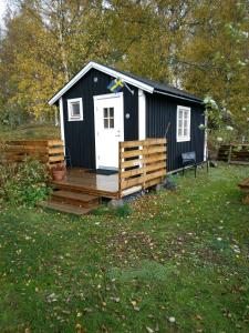 een zwart-witte hut met een houten terras bij Countrycabin Bergslagen stuga in Ramsberg