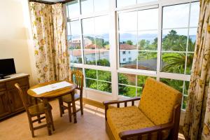 Habitación con mesa, sillas y ventana grande. en Aparthotel Cabicastro en Portonovo