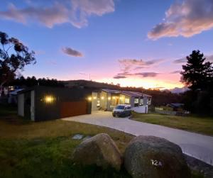 金逹拜恩的住宿－Jindabyne House 1, Modern 3 bedroom home, lake & mountain views with fireplace，日落时在车库前停车