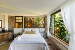 een slaapkamer met een bed en een groot raam bij Feiticeira Guesthouse in Ilhabela