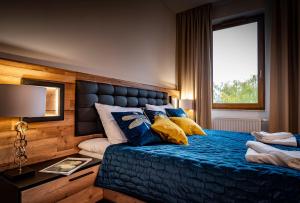 ein Schlafzimmer mit einem blauen Bett mit Kissen und einem Fenster in der Unterkunft APARTHOTEL Wałcz in Wałcz