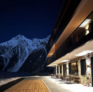 un edificio con mesas y sillas frente a una montaña en Nativo Bergaparts, en Längenfeld