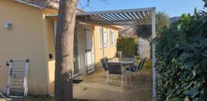 un patio con mesa y sillas bajo una pérgola en L amandier en Vallon-Pont-dʼArc