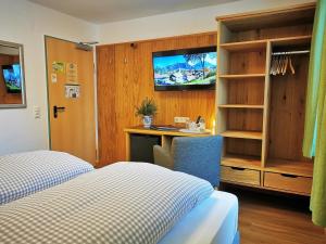 Cette chambre comprend un lit, un bureau et une télévision. dans l'établissement Hotel Waldmann, à Schwangau