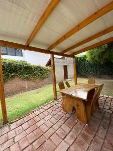 a wooden table and bench on a brick patio at Cabaña en el Centro de Mina Clavero in Mina Clavero