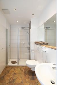 a bathroom with a shower and two sinks and a toilet at Hotel Am Steinberg in Hildesheim