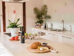 um balcão de cozinha com copos de vinho e um prato de comida em Driftwood Beach House em Kiama