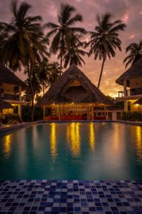 - une piscine en face d'un complexe avec des palmiers dans l'établissement Kupaga Villas Boutique Hotel - Adults Only, à Jambiani