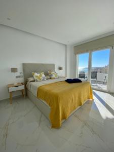 ein weißes Schlafzimmer mit einem Bett mit einer gelben Decke in der Unterkunft Apartamento Ronda III in Fuengirola