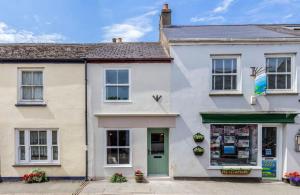 uma casa branca com uma porta verde numa rua em Rosemary Cottage em Bere Alston