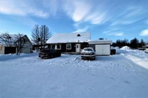 due auto parcheggiate nella neve di fronte a una casa di RIBO Apartment Arctic a Kiruna