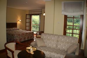 une chambre d'hôtel avec un canapé et un lit dans l'établissement Hotel Valle Las Luiñas, à Soto de Luiña