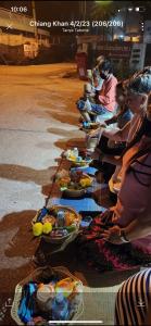 eine Gruppe von Menschen, die um Teller mit Essen herum sitzen in der Unterkunft Welcome holiday in Chiang Khan