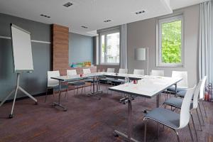 a conference room with tables and chairs and a whiteboard at Aloft München in Munich