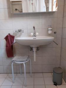 lavabo blanco en un baño con taburete en BnB Elsenerhaus 