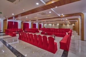 Habitación grande con sillas y mesas rojas y cortinas rojas. en Golden Tulip Tirupati en Tirupati