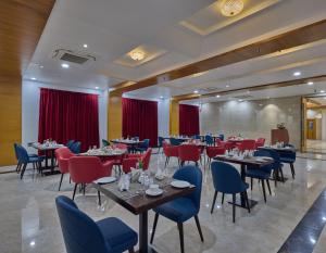 un restaurante con mesas, sillas y cortinas rojas en Golden Tulip Tirupati en Tirupati