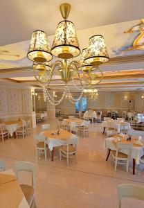 a dining room with tables and chairs and a chandelier at Hotel Rila in Dupnitsa