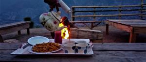 Eine Person kocht Essen auf einem Tisch mit einem Tablett mit Essen. in der Unterkunft Adults Only! Kashmir Eagle Heights Cottage & Restaurant by LMC in Muzaffarabad