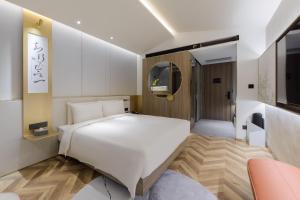 una camera con letto bianco e TV di Atour S Hotel Beijing Zhongguancun Beiwai a Pechino