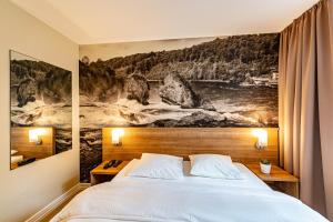 a bedroom with a bed with a painting on the wall at Hotel Kronenhof in Schaffhausen