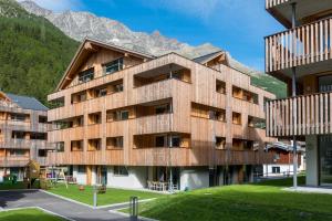 un edificio in legno con montagne sullo sfondo di Montela Hotel & Resort - Suiten a Saas-Grund